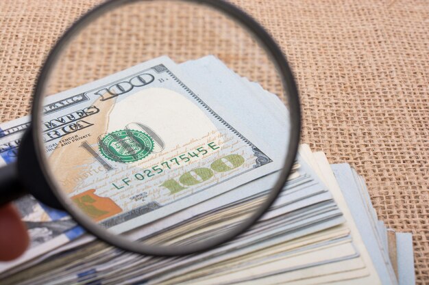 Magnifying glass over the banknote bundle of US dollar