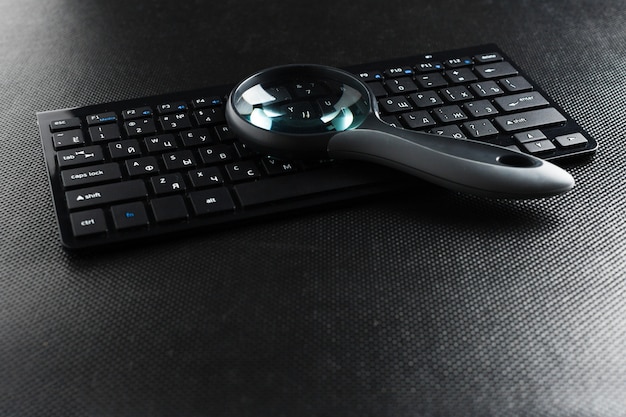 Magnifying glass on black keyboard