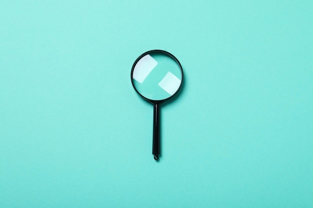 Magnifying glass on blue background top view