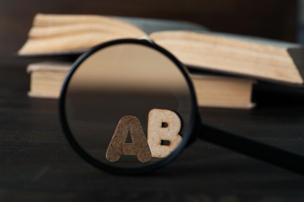 Photo magnifying glass books and letters on wooden background close up