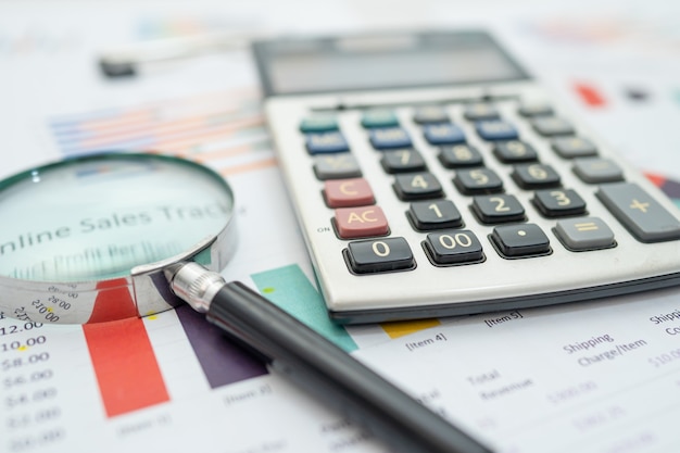 Magnifying glass  and calculator on charts graphs paper