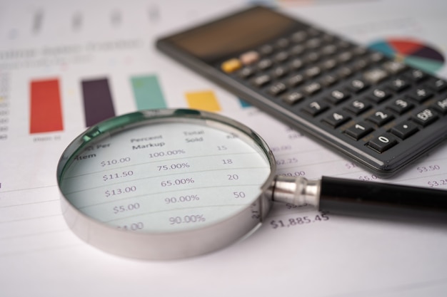 Magnifying glass and calculator on graph paper.