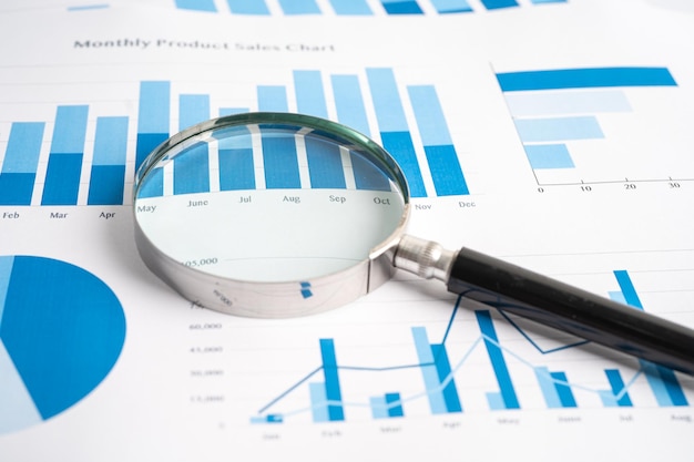 Magnifying glass on charts graphs paper Financial development Banking Account Statistics Investment Analytic research data economy Stock exchange trading Business office company meeting concept