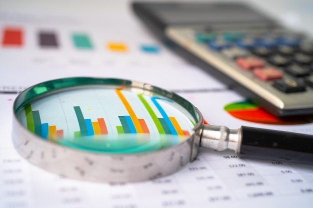 Magnifying glass on charts graphs paper.