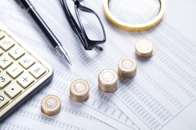 Magnifying glass, coins, eyeglasses, calculator, pen on financial documents. Business. Finance