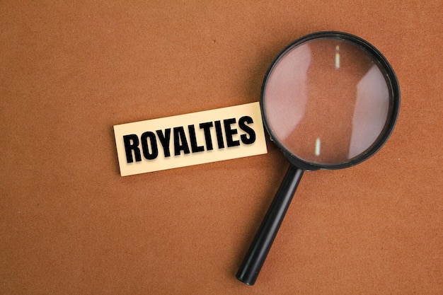 magnifying glass and colored paper with the word Royalties royalty free concept