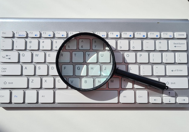 Photo magnifying glass on computer keyboard and searching for information on internet