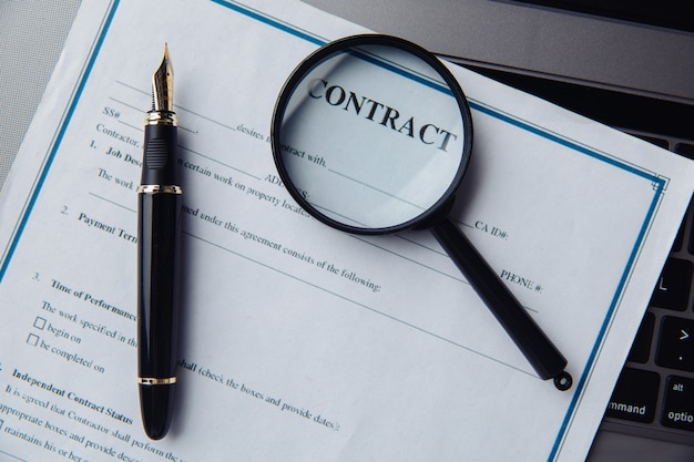 A magnifying glass on the contract liying on a keyboard.