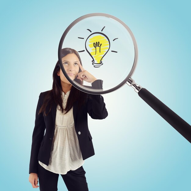 Magnifying glass examines the idea of a young businesswoman