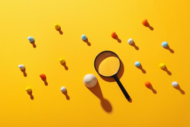 Magnifying glass figures and ball on yellow background top view