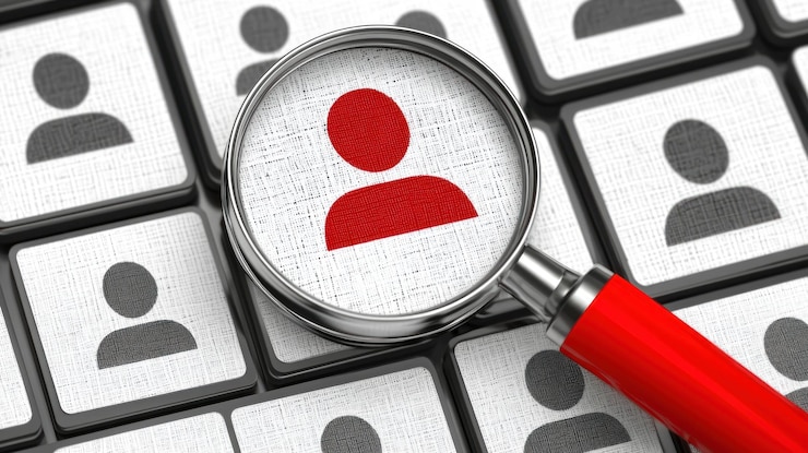 Photo magnifying glass focusing on a red profile icon among many gray ones recruitment selection and finding the right candidate concept