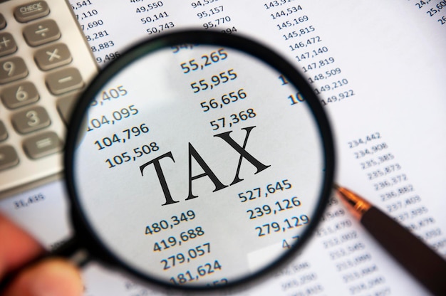 Magnifying glass focusing on TAX word on analysis paper Tax concept