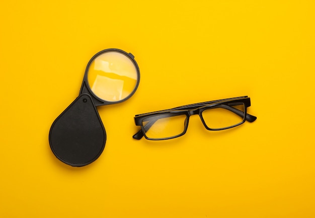 Magnifying glass and glasses on yellow.