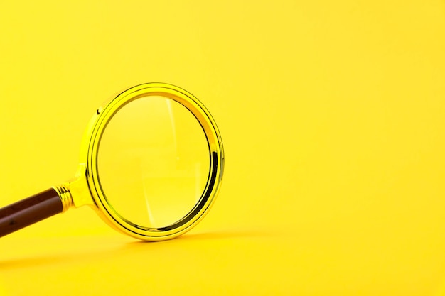 Magnifying glass in a gold frame on a yellow 