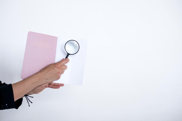 Magnifying glass in hand on the background of a notebook