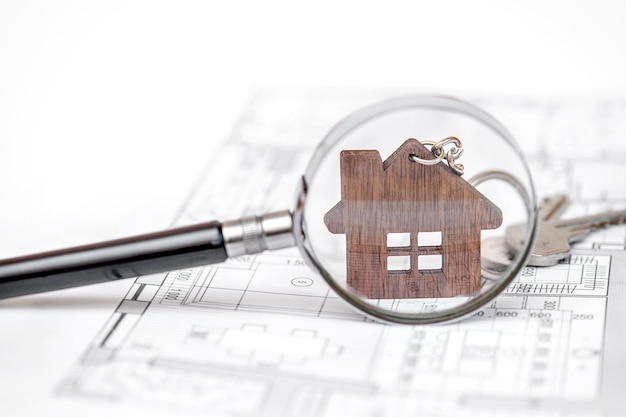 Photo a magnifying glass over a house on top of a blueprint