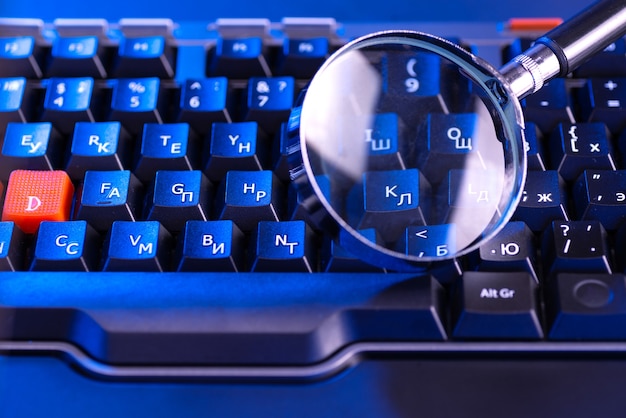 Magnifying glass on the keys of a black computer keyboard.