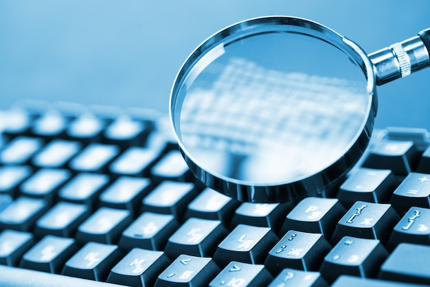 Magnifying glass on the keys of a black computer keyboard.