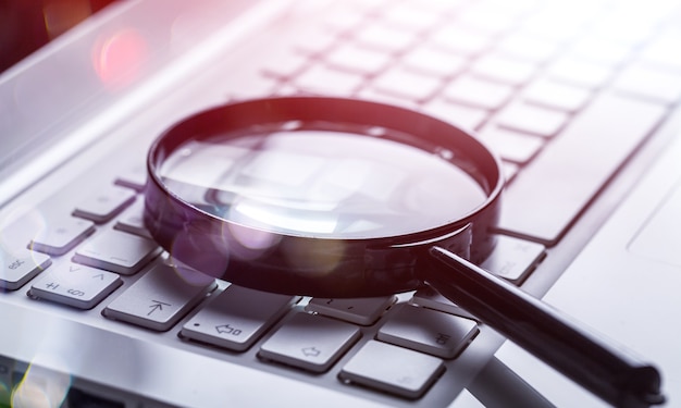 Magnifying glass on laptop keyboard close-up