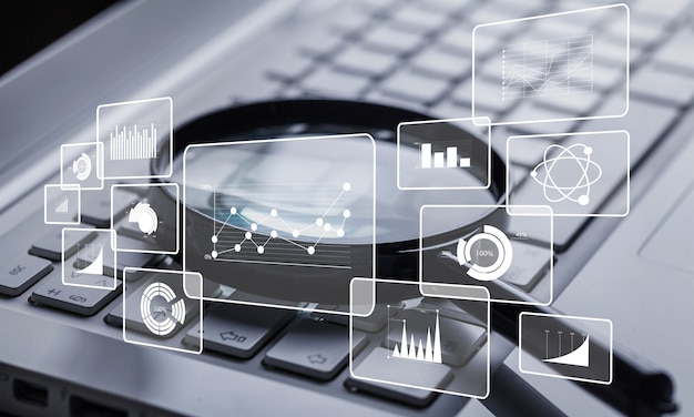 magnifying glass on laptop keyboard closeup with infographics