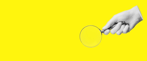 Photo magnifying glass lens in hand for search find study yellow banner background with copy space