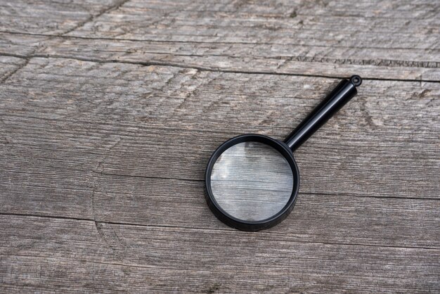 Photo the magnifying glass lies on a gray wooden background