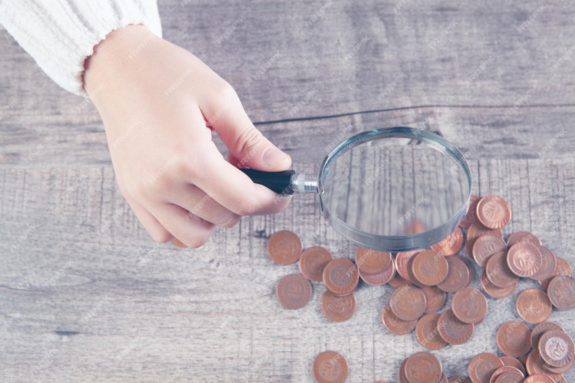 Premium Photo  Magnifying glass looks at the coins on the table