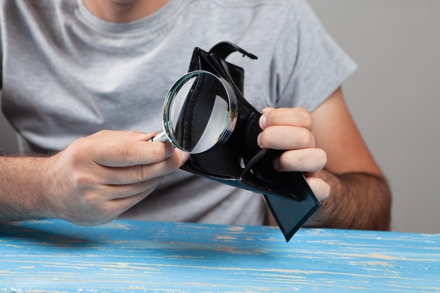 Magnifying glass looks at an empty wallet