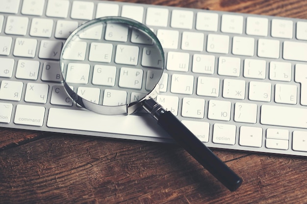 Magnifying glass lying on computer keyboard