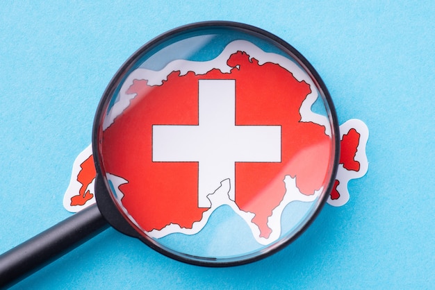 Photo magnifying glass on map of switzerland. concept of closer look the european country, study its culture traditions and religion