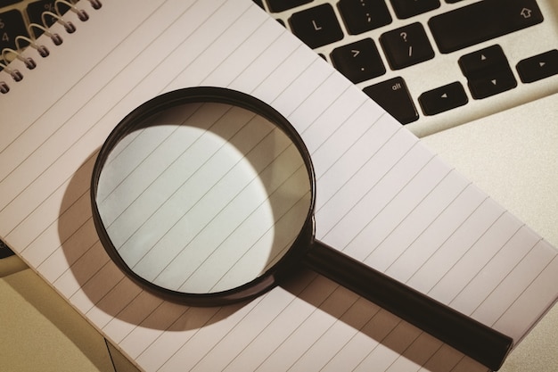 Magnifying glass and notepad on laptop