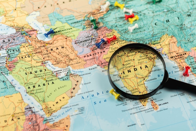 Фото Увеличительное стекло на карте мира селективного внимания в индии. - экономическая и бизнес-концепция.