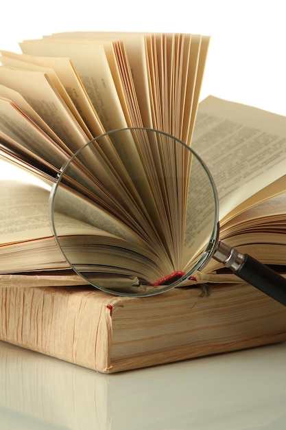 Увеличительное стекло и открытая книга изолированы на белом