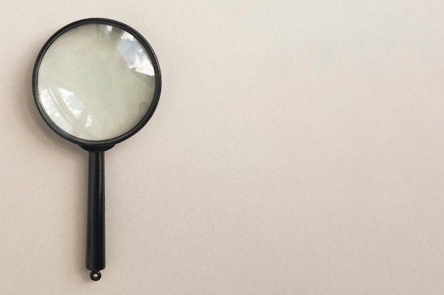 Magnifying glass over pale beige background magnifier as concept of finding answers