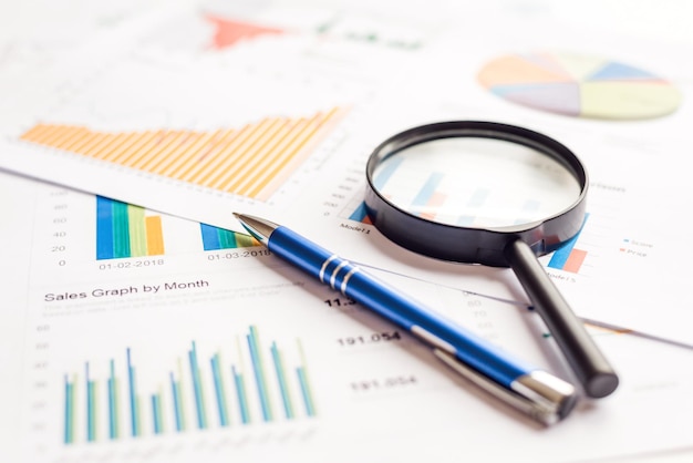 Увеличительное стекло и ручка на финансовых графиках Годовой отчет о документах
