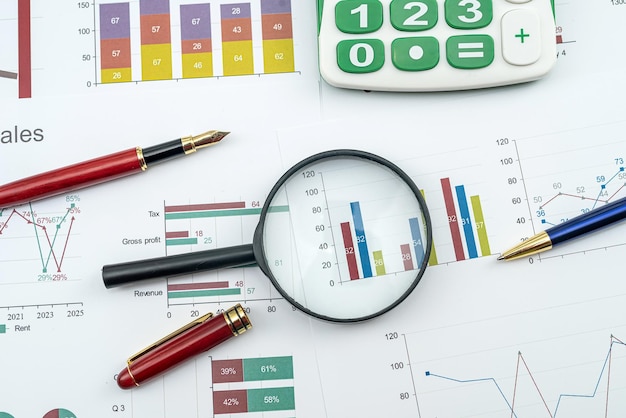 Magnifying glass and pen on financial charts graphs