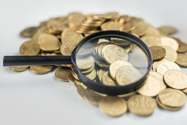 Magnifying glass on a pile of money coins on a glass office table financial position economic analysis