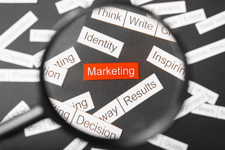 Magnifying glass over the red inscription marketing cut out of paper