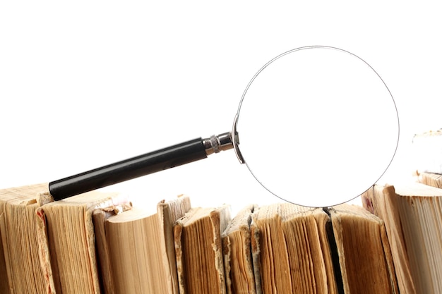 Magnifying glass over the stack of books isolated on white