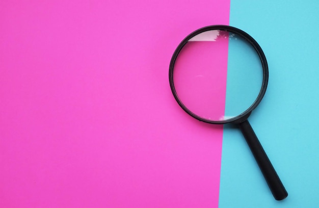 A magnifying glass on two tone the pink and blue background