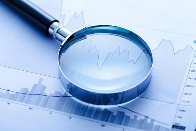 Magnifying glass with business graphs