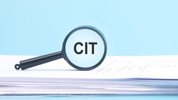 Увеличительное стекло с надписью корпоративного подоходного налога CIT на синем фоне