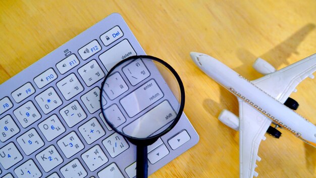 Фото Увеличительное стекло с компьютерной клавиатурой и моделью самолета на столе