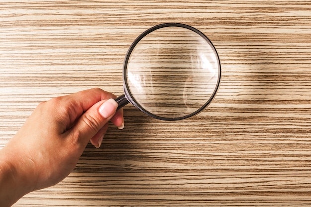 Magnifying glass on the wooden background