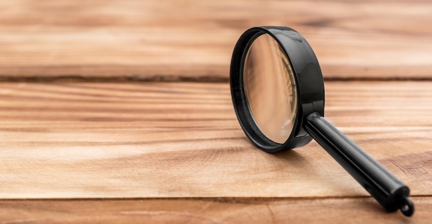 Photo magnifying glass on wooden table close up