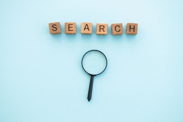 Magnifying glass and word search written wooden cubes on blue background Search concept