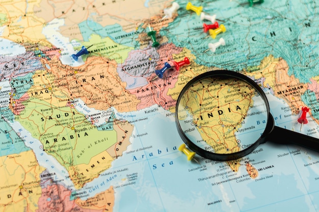 Photo magnifying glass on the world map selective focus at india. - economic and business concept.