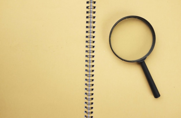 a magnifying glass on a yellow notebook