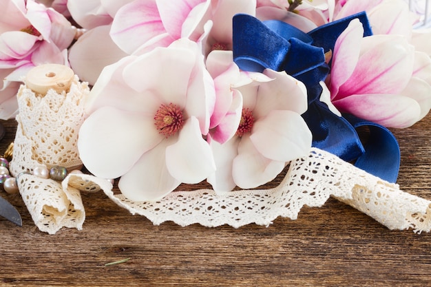 Свежие цветы магнолии с жемчугом и винтажным кружевом на деревянном столе