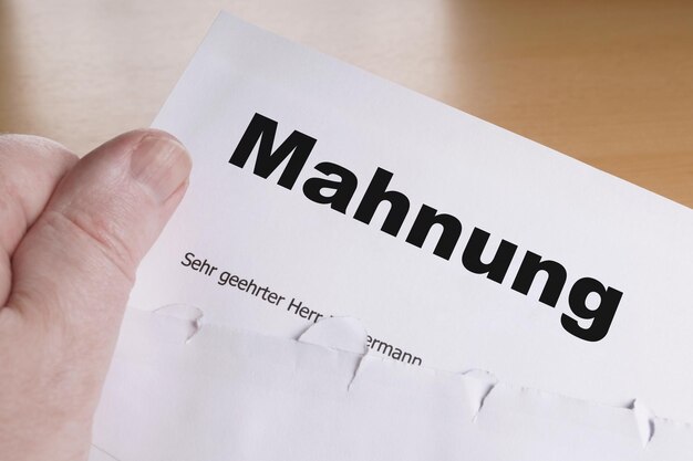Foto mano maschio di mahnung che tiene la lettera di sollecito o di sollecito tedesca